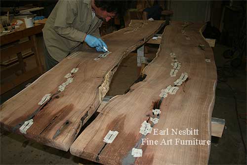 Earl pouring epoxy in cracks on mesquite slabs for custom made live edge dining table